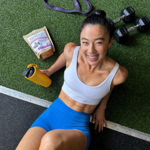 Fitness trainer Meagan Kong resting after a workout and holding a Sparkle Daily shaker tin with Muscle Boost collagen protein powder.